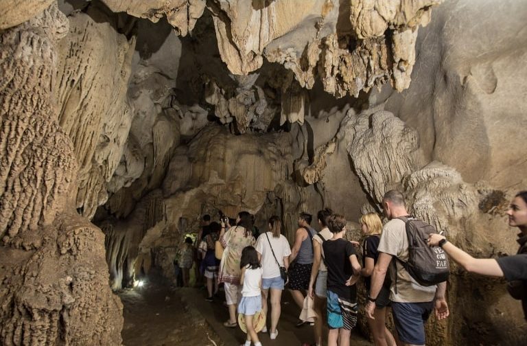 Du khách tham quan hang động đá vôi trên vịnh Lan Hạ dưới sự hướng dẫn của hướng dẫn viên du lịch. 