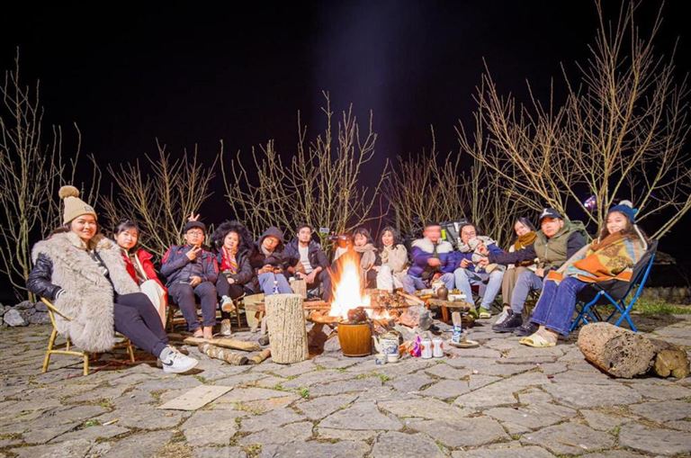 Khách du lịch đốt lửa trại và ngồi quây quần bên nhau trò chuyện, lắng nghe những câu chuyện văn hoá địa phương. 